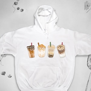 Puede incluir: Sudadera con capucha blanca con un gráfico de cuatro bebidas de café con hielo diferentes. Las bebidas están todas en vasos transparentes con diferentes ingredientes y pajitas.