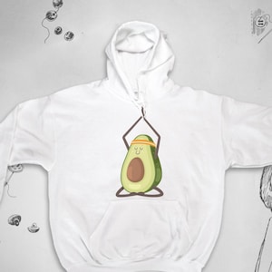 May include: White hooded sweatshirt with a cartoon avocado doing yoga. The avocado is green with a brown seed and has a yellow headband.