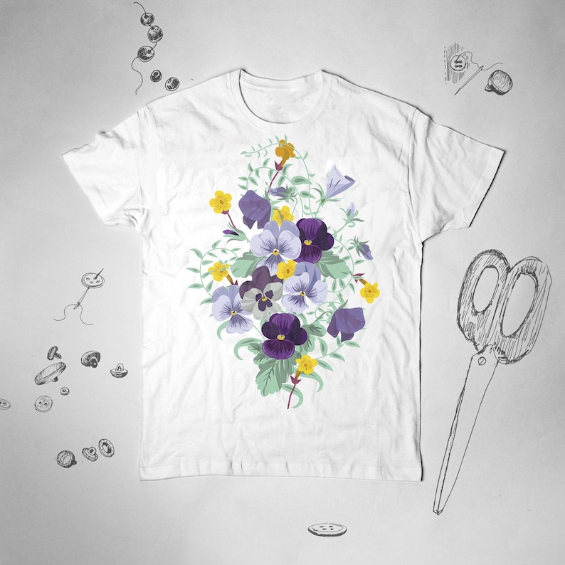 May include: White t-shirt with a floral print of purple and yellow pansies. The flowers are arranged in a bouquet shape and are surrounded by green leaves.