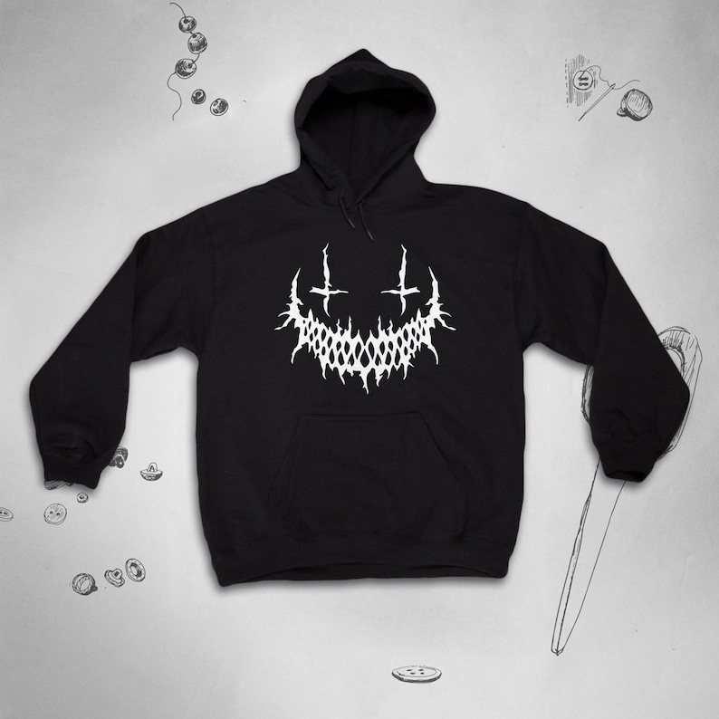 May include: Black hooded sweatshirt with a white graphic of a stylised smiling face with two crosses above it.