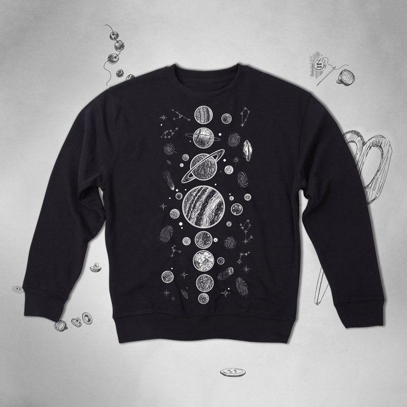 Peut inclure: Sweat-shirt noir avec un imprim&eacute; graphique blanc de plan&egrave;tes et d'&eacute;toiles. Le graphique est centr&eacute; sur le devant du sweat-shirt.