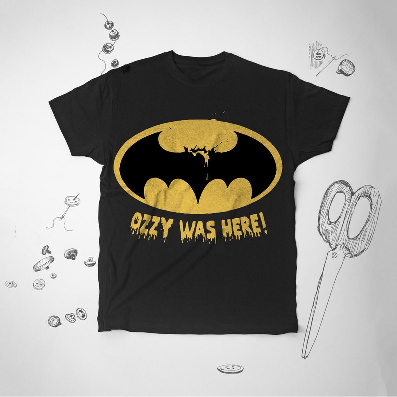 May include: Black t-shirt with a yellow Batman logo and the text "Ozzy Was Here!" in yellow dripping letters.