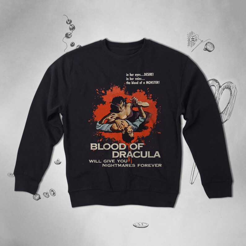 May include: Black sweatshirt with a vintage movie poster design featuring a couple in a dramatic scene. The poster reads "Blood of Dracula" and "Will Give You Nightmares Forever".