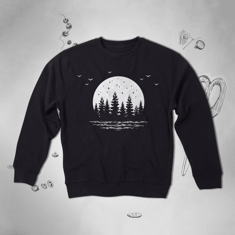 May include: Black sweatshirt with a white graphic design of a full moon with stars and a silhouette of a forest in front of it.