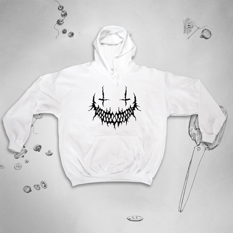 May include: White hooded sweatshirt with a black graphic of a stylised, toothy grin with two crosses above it.