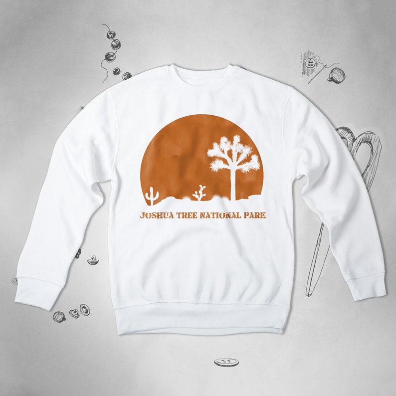Peut inclure: Sweat-shirt blanc avec un graphique de coucher de soleil brun et le texte "Joshua Tree National Park".