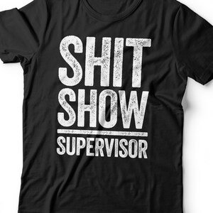 May include: Black t-shirt with white text that reads "SHIT SHOW SUPERVISOR" in a distressed font.