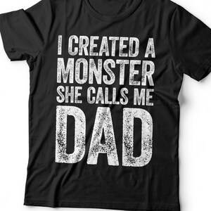 May include: Black t-shirt with white text that reads "I created a monster she calls me dad".