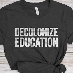 May include: A dark heather grey t-shirt with the text "DECOLONIZE EDUCATION" printed in white.