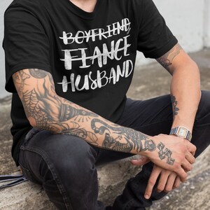 May include: A black t-shirt with white text that reads "Boyfriend Fiance Husband".