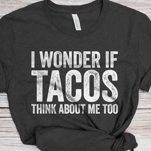 May include: A dark gray t-shirt with the text "I wonder if tacos think about me too" printed in white.
