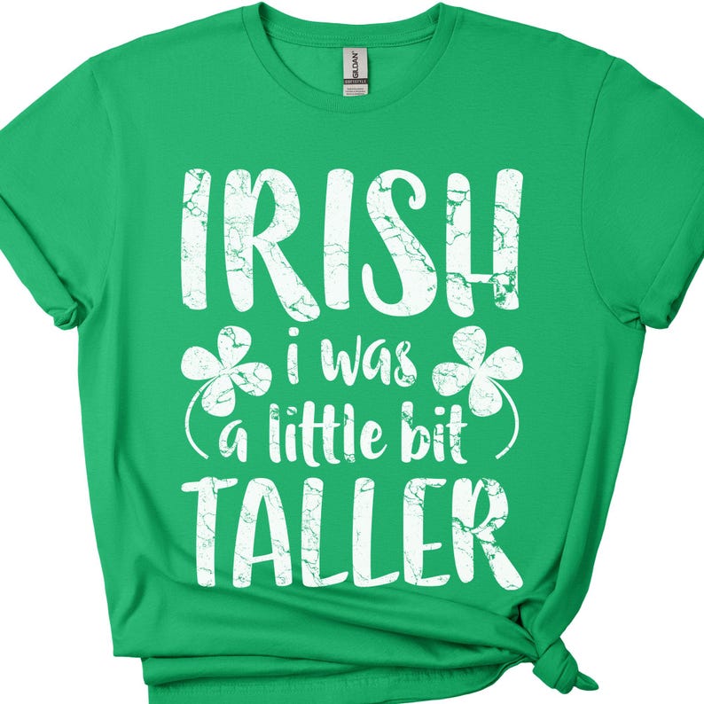 K&ouml;nnte beinhalten: Gr&uuml;nes T-Shirt mit wei&szlig;em Text, der "Irish I was a little bit taller" lautet, mit Kleeblatt-Designs auf beiden Seiten des Textes.