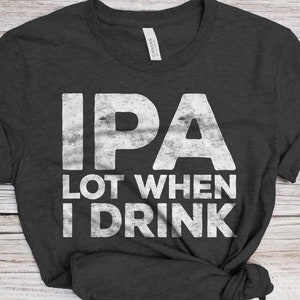 May include: A dark gray t-shirt with a white distressed graphic that reads "IPA Lot When I Drink".