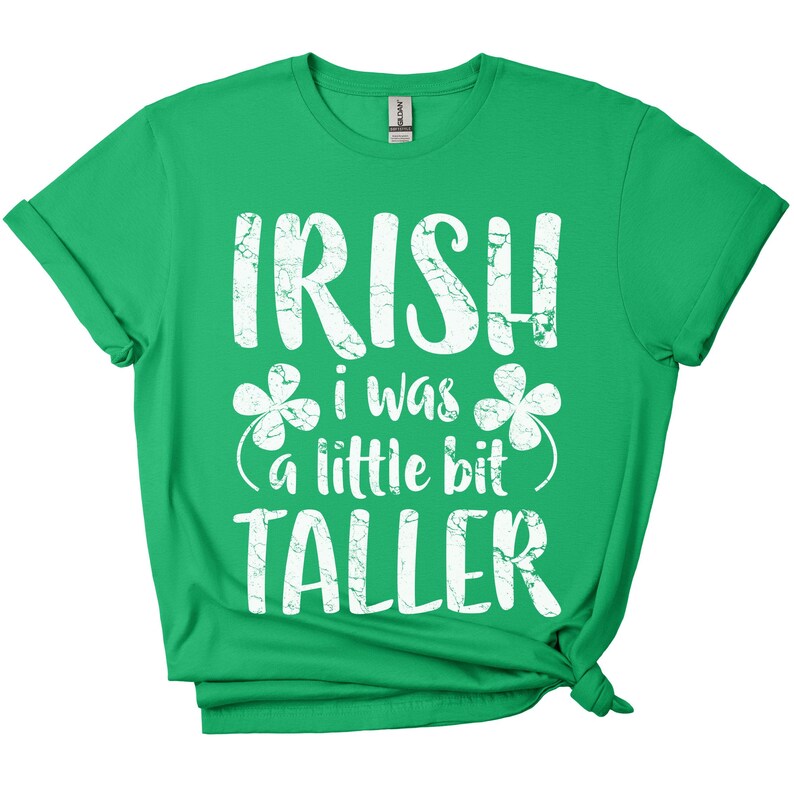 K&ouml;nnte beinhalten: Gr&uuml;nes T-Shirt mit wei&szlig;em Text, der "Irish I was a little bit taller" lautet, mit Kleeblatt-Grafiken.