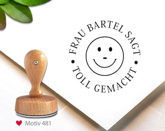 May include: A wooden stamp with a smiley face design and the text "FRAU BARTEL SAGT TOLL GEMACHT". The stamp has a wooden handle and a round base. The image also includes the text "Motiv 481".