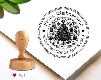 May include: A black and white round rubber stamp with the text "Frohe Weihnachten wünschen Nancy, Tom & Lena" and a stylized Christmas tree with ornaments and gifts. The stamp is on a white background.