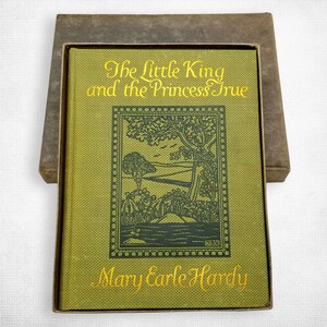 Puede incluir: Un libro de tapa dura verde con el título "The Little King and the Princess True" de Mary Earle Hardy. La portada presenta una ilustración en blanco y negro de un paisaje con árboles y un río.