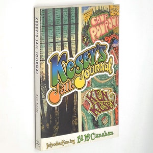Puede incluir: Un libro de tapa dura titulado "Kesey's Jail Journal" de Ken Kesey. La portada presenta letras e ilustraciones psicodélicas coloridas. El lomo del libro muestra el título y el nombre del autor. La introducción es de Ed McClanahan.