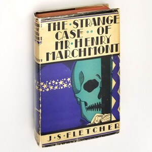 May include: A vintage hardcover book with a purple and gold cover. The title is "The Strange Case of Mr. Henry Marchmont" by J.S. Fletcher. The cover features a green skull with a black eye socket.