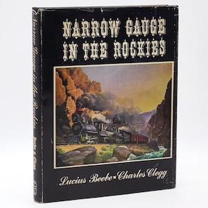 May include: A hardcover book titled "Narrow Gauge in the Rockies" with a black cover. The cover features a painting of a steam train traveling through a mountain landscape. The authors' names, Lucius Beebe and Charles Clegg, are printed at the bottom.