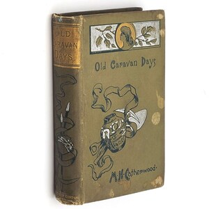 May include: A vintage green book titled "Old Caravan Days" by M.H. Catherwood. The cover features a decorative illustration of a pot with a swirling design and a woman's profile.