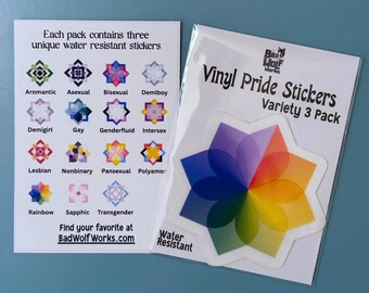 May include: A pack of Vinyl Pride Stickers with a variety of designs, including a rainbow flower and other geometric shapes. The pack includes three unique water-resistant stickers. The text on the packaging reads "Vinyl Pride Stickers Variety 3 Pack."