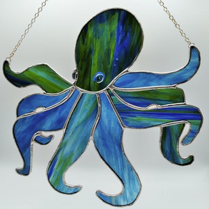 Könnte beinhalten: Ein Buntglas-Oktopus mit blauen und grünen Wirbeln. Der Oktopus hat acht Tentakel und ein großes Auge.