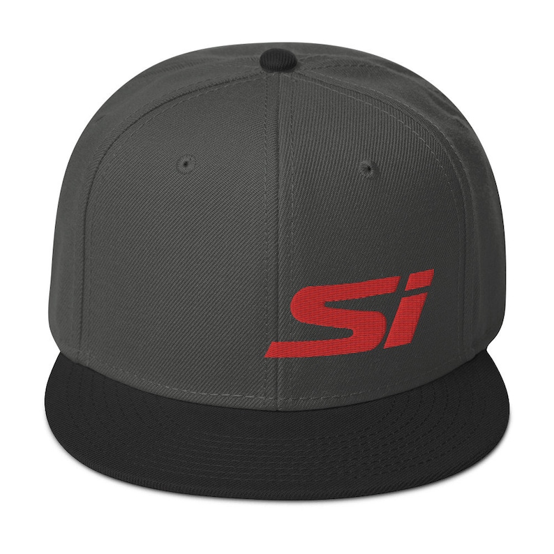 May include: A flat-brimmed baseball cap in charcoal gray with a black brim. The cap features the red letters "SI" on the front. The cap has a structured fit and a snapback closure.