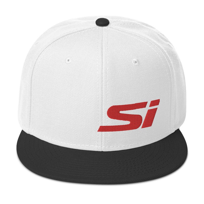 May include: A white flat-brimmed baseball cap with a black brim and a black button on top. The red letters "SI" are printed on the front of the cap. The cap is a classic style.