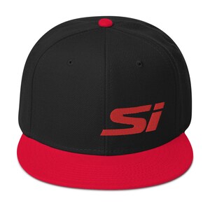 May include: A black and red baseball cap with the letters "SI" embroidered in red on the front. The cap has a flat brim and a red button on top.