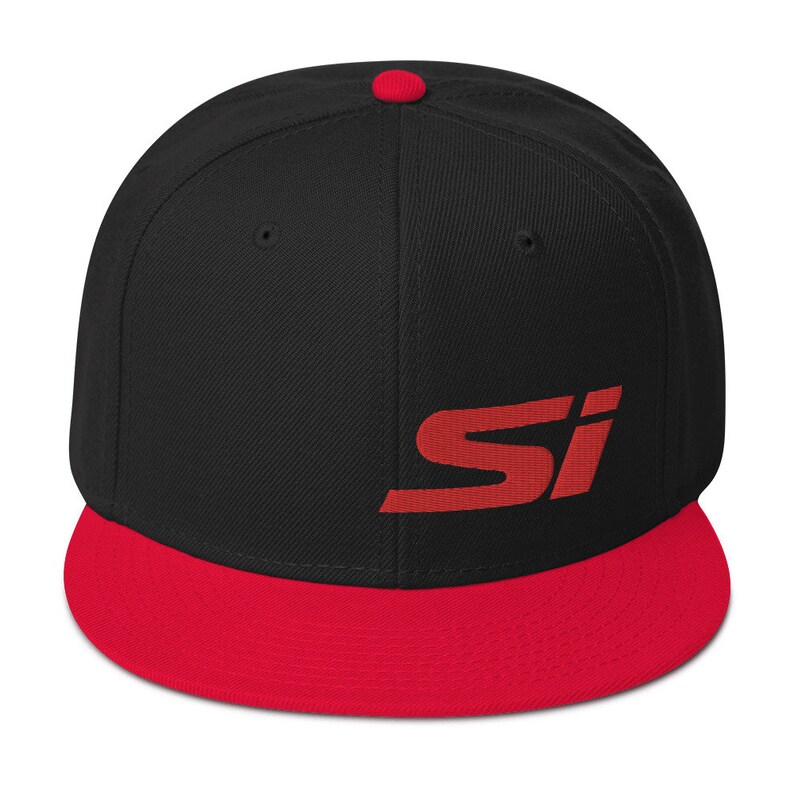 May include: A black and red baseball cap with the letters "SI" embroidered in red on the front. The cap has a flat brim and a red button on top.