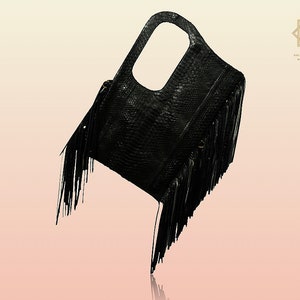 Peut inclure: Sac à main en cuir noir avec des détails en franges. Le sac a une poignée supérieure et une fermeture à rabat.