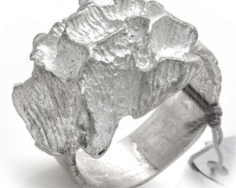 Puede incluir: Un anillo de plata con un diseño texturizado y orgánico. El anillo está hecho de una sola pieza de metal y tiene una banda ancha.