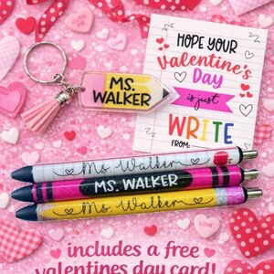 May include: A Valentine's Day gift set featuring a pencil-shaped keychain and pens, all personalized with "Ms. Walker." The set includes a free Valentine's Day card. The background is pink with heart-shaped decorations.
