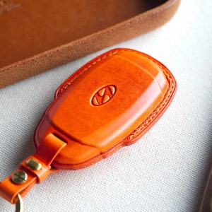 May include: Orange leather key fob with a metal key ring and the Hyundai logo embossed on the front.