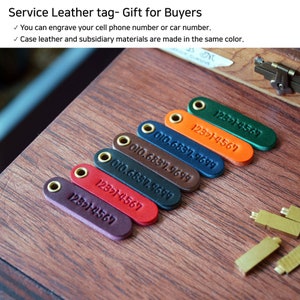 May include: Seven leather key tags in different colors with phone numbers and a close-up of the metal stamps used to create the tags.