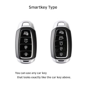 May include: Two black car key fobs with silver accents. The key fobs have multiple buttons, including a button labeled "HOLD".