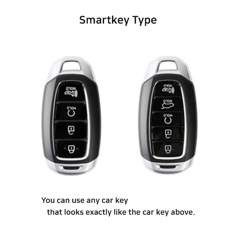 May include: Two black car key fobs with silver accents. The key fobs have multiple buttons, including a button labeled "HOLD".