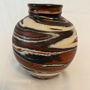 May include: A round ceramic vase with a narrow neck and a wide body. The vase features a swirling pattern of cream, dark brown, black, and reddish-brown colors. The rim of the vase is a glossy dark brown.