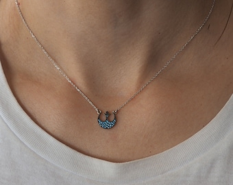 May include: A silver chain necklace with a small blue and silver pendant in the shape of the Rebel Alliance symbol from Star Wars.
