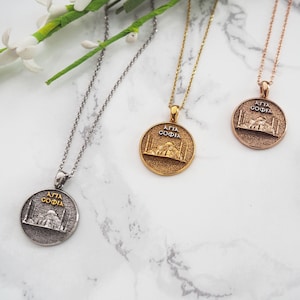 Può includere: Tre collane in argento, oro e oro rosa con un ciondolo rotondo che presenta un'immagine dettagliata della moschea di Santa Sofia a Istanbul, Turchia. Il ciondolo ha il testo "AYA SOFIA" scritto in lettere dorate.