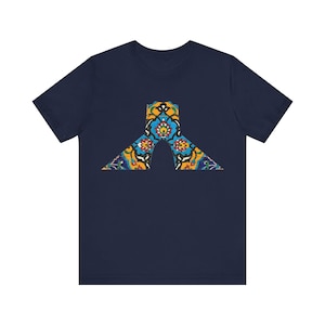 May include: A navy blue t-shirt with a colorful geometric design in the center. The design features a variety of colors, including blue, green, yellow, and red.