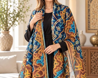 May include: A lightweight rectangular scarf featuring a complex geometric and floral pattern in shades of deep blue, golden yellow, and brown, draped over a solid black long-sleeved dress with a simple round neckline.