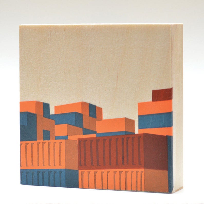 May include: A wood block art print with a geometric design of a building with orange, brown, and blue colors.