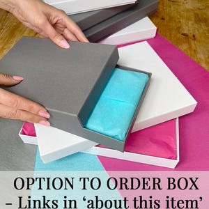 May include: A stack of white and gray gift boxes with a blue tissue paper inside the top box. The text "OPTION TO ORDER BOX - Links in 'about this item'" is visible at the bottom of the image.