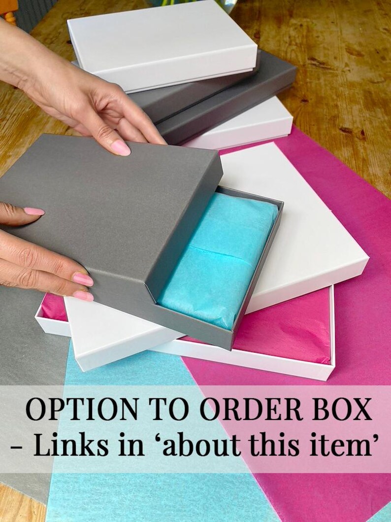 May include: A stack of white and gray gift boxes with a blue tissue paper inside the top box. The text "OPTION TO ORDER BOX - Links in 'about this item'" is visible at the bottom of the image.