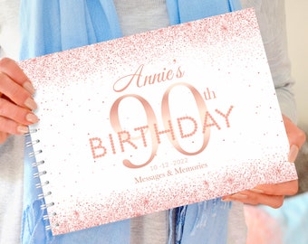 Op de afbeelding: Een wit en roze glitter scrapbook met de tekst "Annie's 90th Birthday" en de datum "10-12-2022" met de woorden "Messages & Memories" eronder.