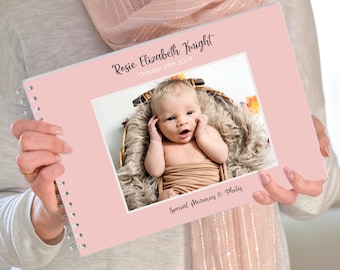 May include: Pink baby memory book with a photo of a baby girl on the front cover. The book has the text "Rosie Elizabeth Knight" and "October 29th 2019" on the front cover. The text "Special Memories & Photos" is printed below the photo.