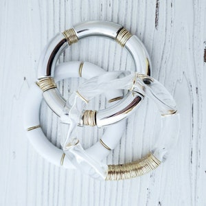 May include: Three bracelets, one silver with gold accents, one white with gold accents, and one clear with gold accents.