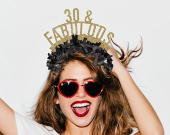 Puede incluir: Una mujer con una camiseta blanca con el texto "I already love you" y una diadema negra con letras doradas brillantes que dicen "30 & FABULOUS". Lleva gafas de sol rojas en forma de corazón y tiene el pelo recogido hacia atrás.